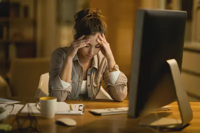 Woman in front of a computer, looking frustrated